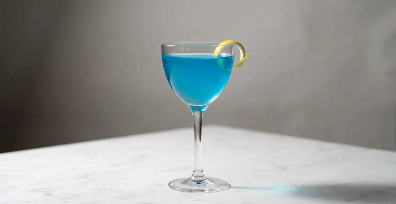 Blue Lagoon servi dans une coupe élégante Nick & Nora sur fond épuré avec éclairage dramatique