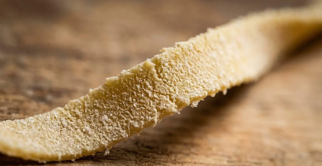 Gros plan sur la texture poreuse des tagliatelles qui accroche la sauce bolognaise