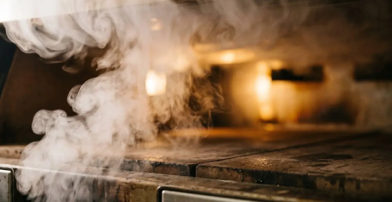 Scène minimaliste montrant l'atmosphère humide créée par la vapeur dans un four lors de la cuisson du pain